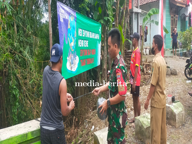 Babinsa Pasang Spanduk Larangan Buang Sampah Sembarangan Bersama Masyarakat